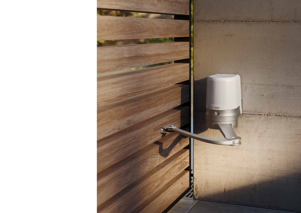 Able AR-Series Articulated Swing Gate Motors with a white motor housing and silver articulated arm on a wooden slat gate