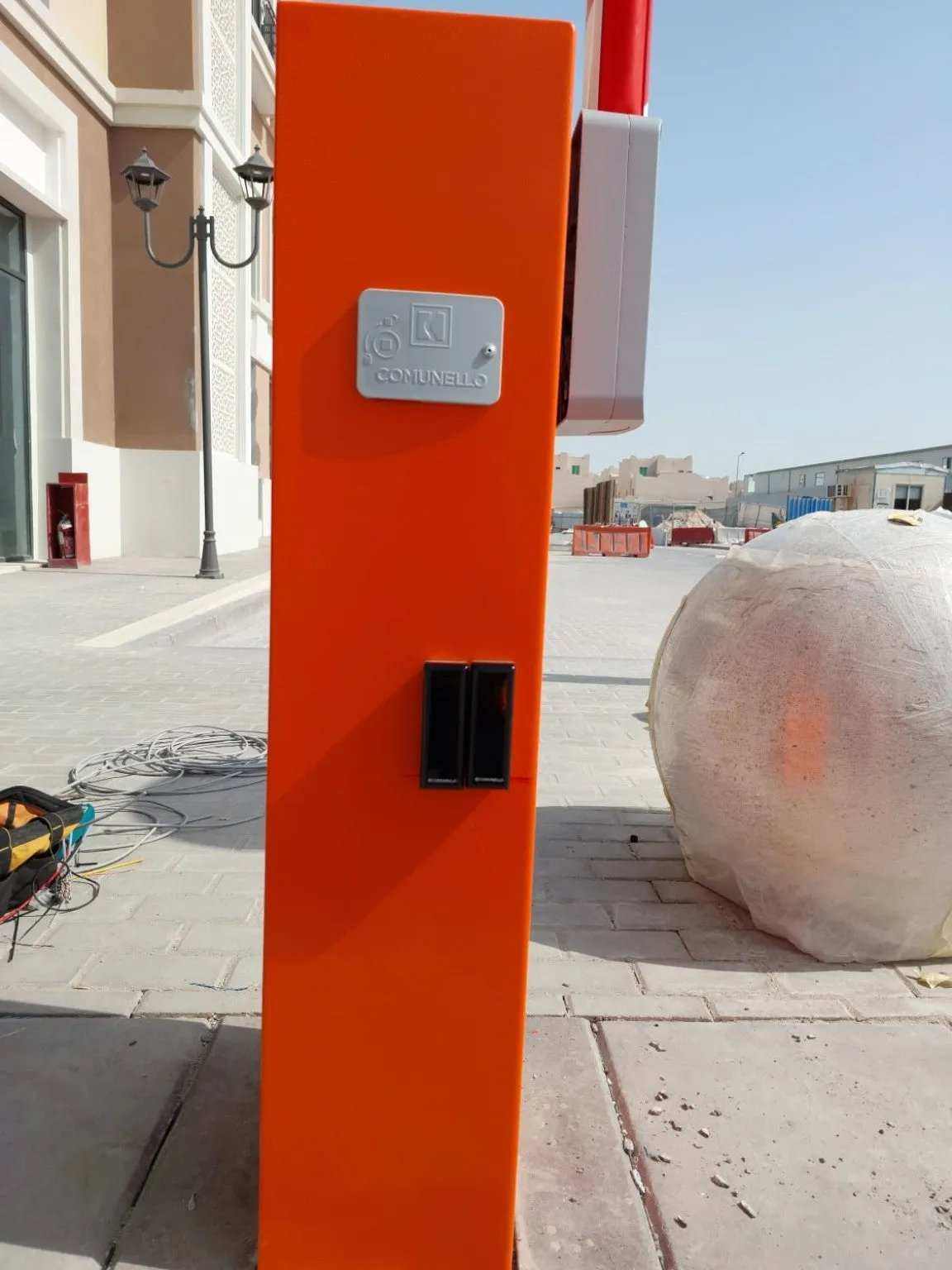 Comunello BORDER 400 Automatic Parking Barrier with an orange metal cabinet, silver logo badge and black recessed panel