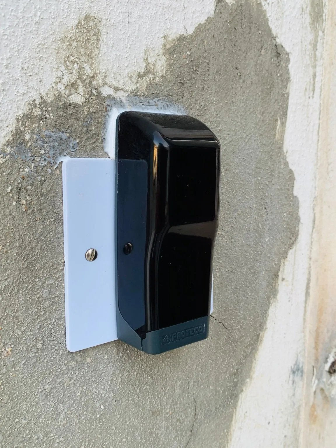 Sliding gate photocell for Comunello FORT 1500 Sliding Gate Motor, with a black plastic housing and grey mounting bracket.