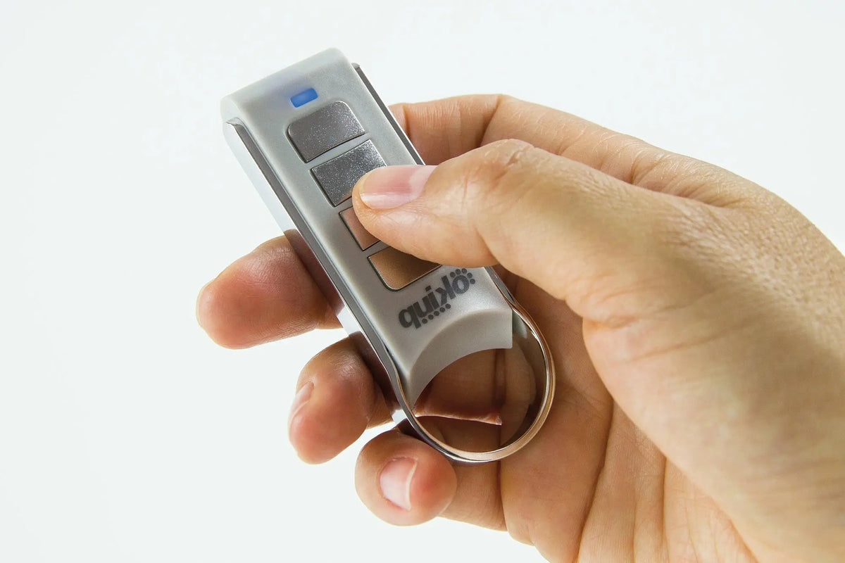 Quiko 4-Channel Gate Remote in silver and grey plastic with rectangular buttons, a blue indicator and metal keyring
