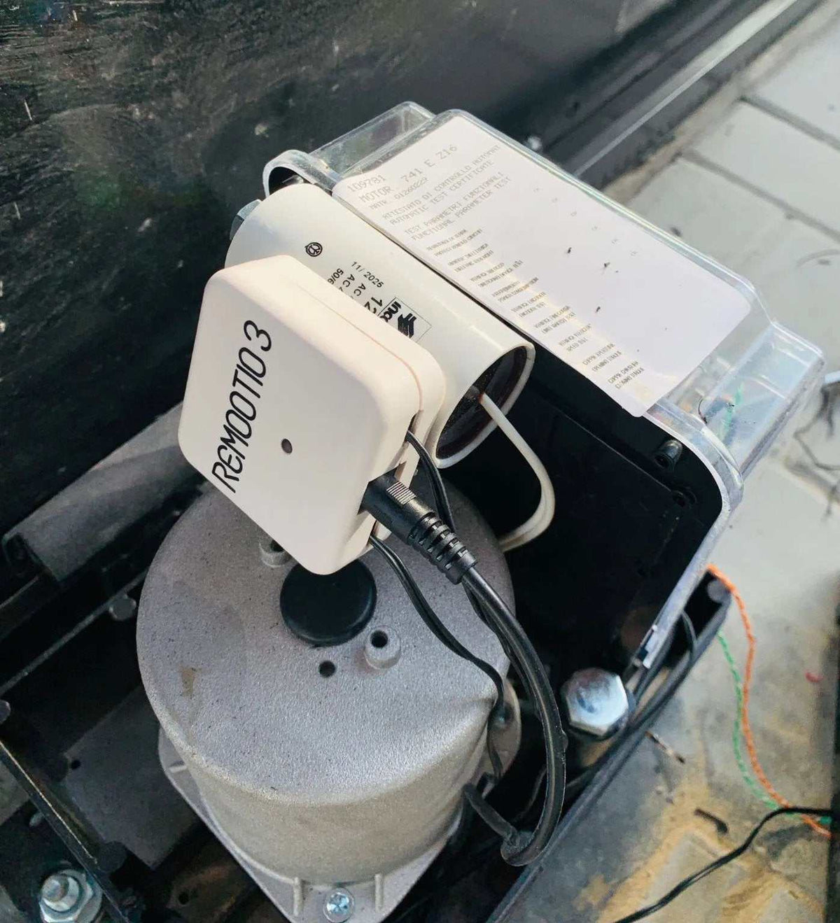 White Remootio 3 smart gate controller in Qatar, a compact rounded rectangular unit with a black logo and connected cables.