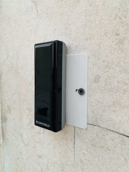 Comunello DART SLIM Gate Safety Photocells, slim black plastic sensor with a glossy front and Comunello logo, mounted on a white bracket.