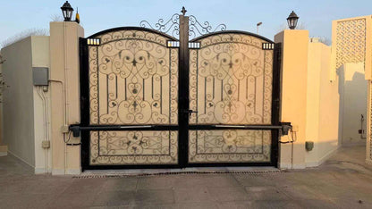 Swing gate operator Proteco ASTER 4 NEW with black metal actuator arms fitted to an ornate double-leaf gate