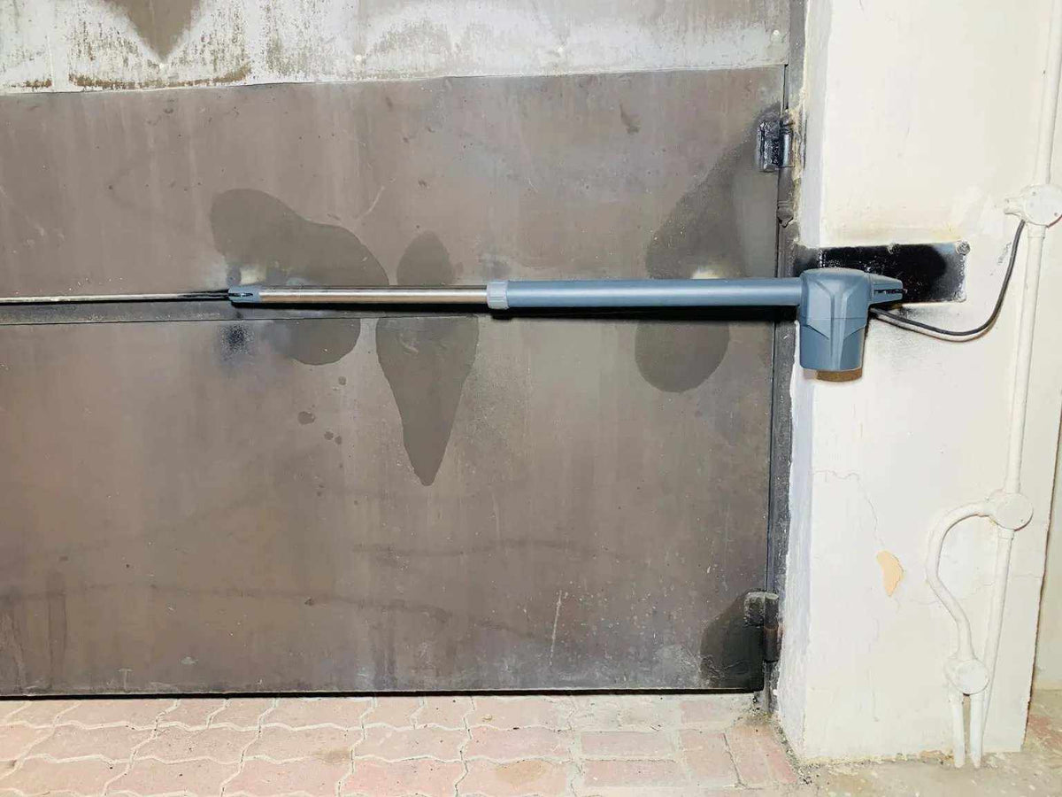 Swing gate operator Proteco ASTER 4 NEW with a grey metal housing and black telescopic arm fixed to a solid gate