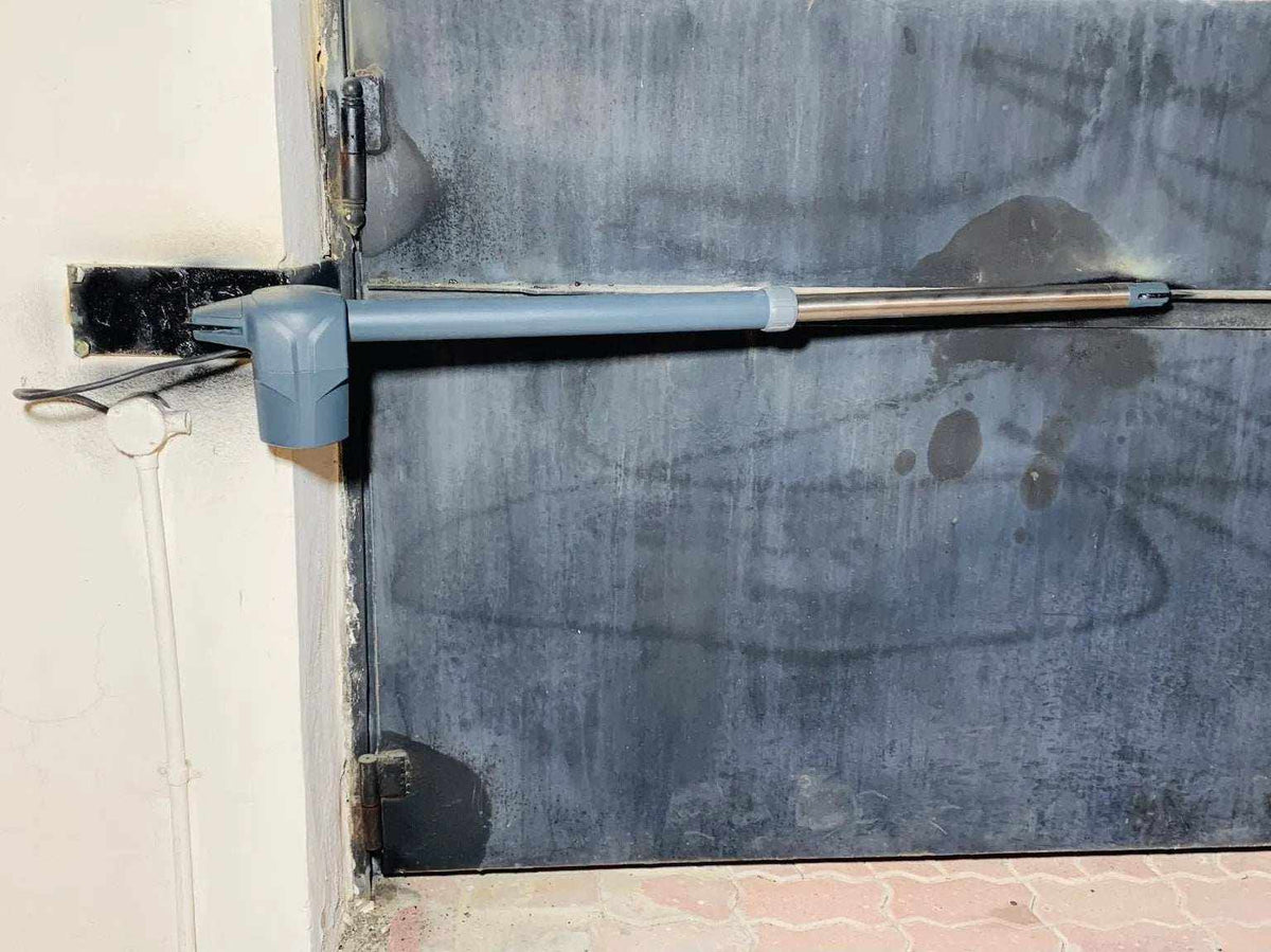 Swing gate operator Proteco ASTER 4 NEW with a grey metal housing and telescopic arm fitted to a solid steel gate