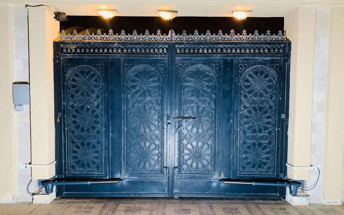 Proteco Telescopic Swing Gate Operator with white housings and dark arms fitted to an ornate black metal double gate