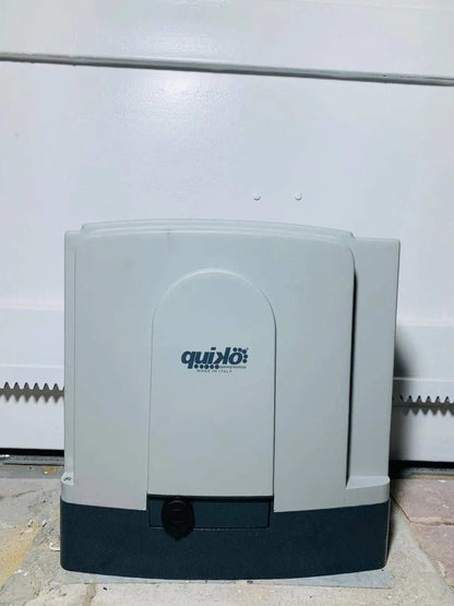 Quiko MOOVY Sliding Gate Operator in a light gray and dark gray plastic housing, with a central Quiko logo and key release.