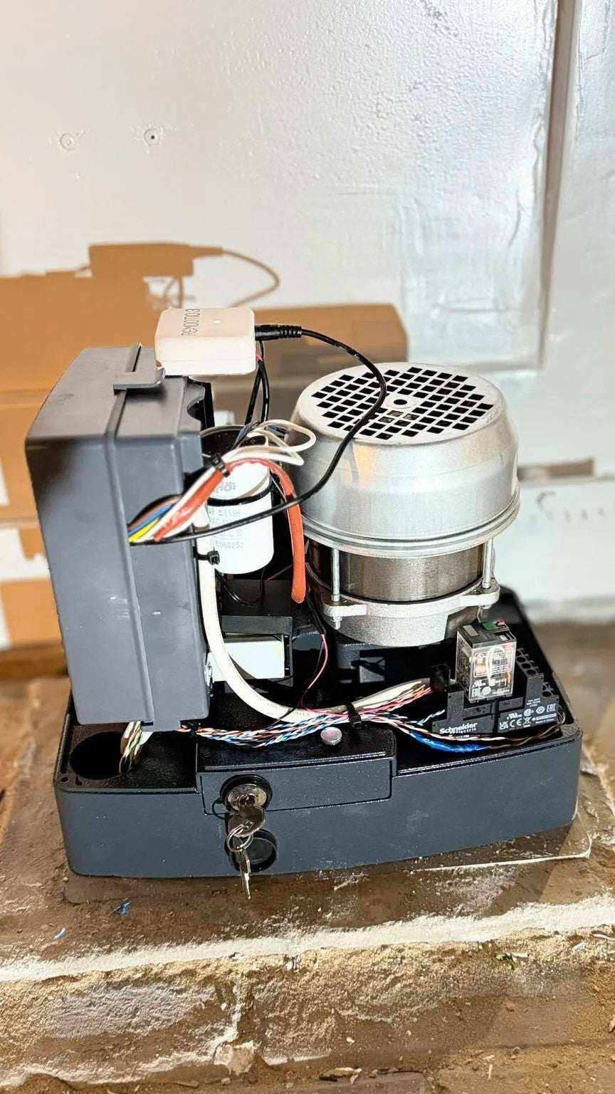 Quiko MOOVY sliding gate operator in Qatar with a gray housing, exposed wiring and a round silver motor assembly.