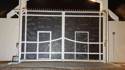 Quiko MOOVY sliding gate operator in Qatar, white metal sliding gate with dark panels and pedestrian doors