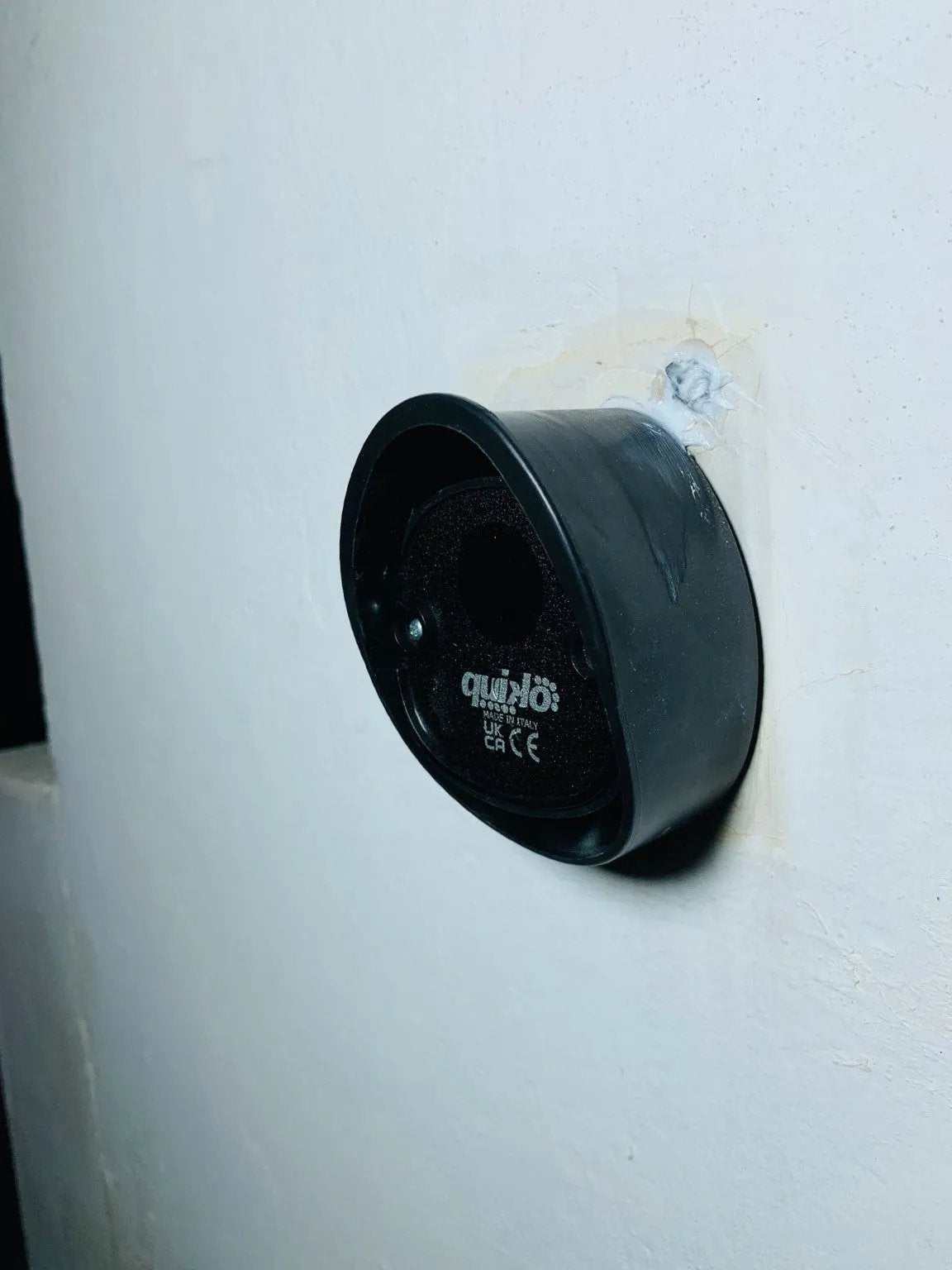 Quiko MOOVY Sliding Gate Operator, black circular housing with a recessed face and visible Quiko branding mounted on a white gate.