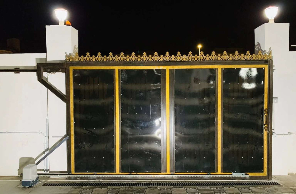 Quiko MOOVY Sliding Gate Operator shown with a black metal sliding gate, gold trim, and ornate gold cresting.