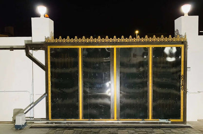 Quiko MOOVY Sliding Gate Operator shown with a black metal sliding gate, gold trim, and ornate gold cresting.
